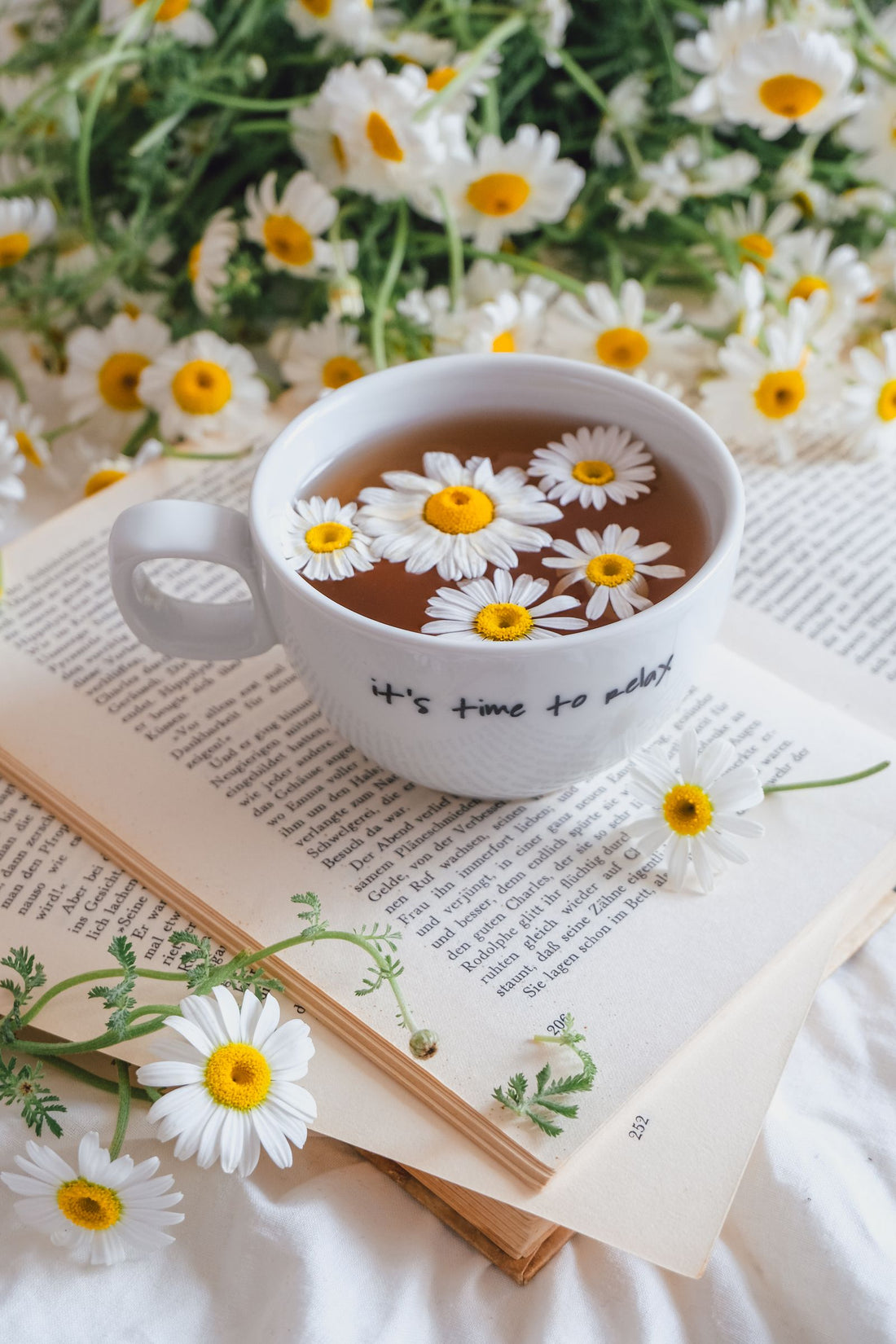 Chamomile tea with daisies and an open book