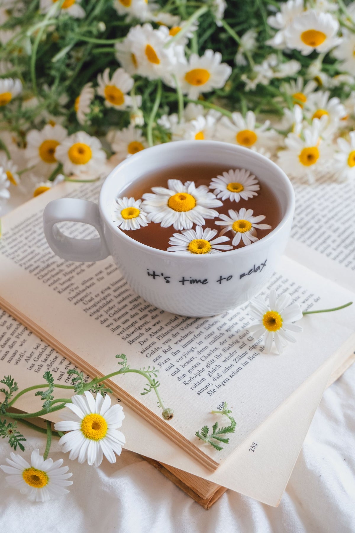 Chamomile tea with daisies and an open book