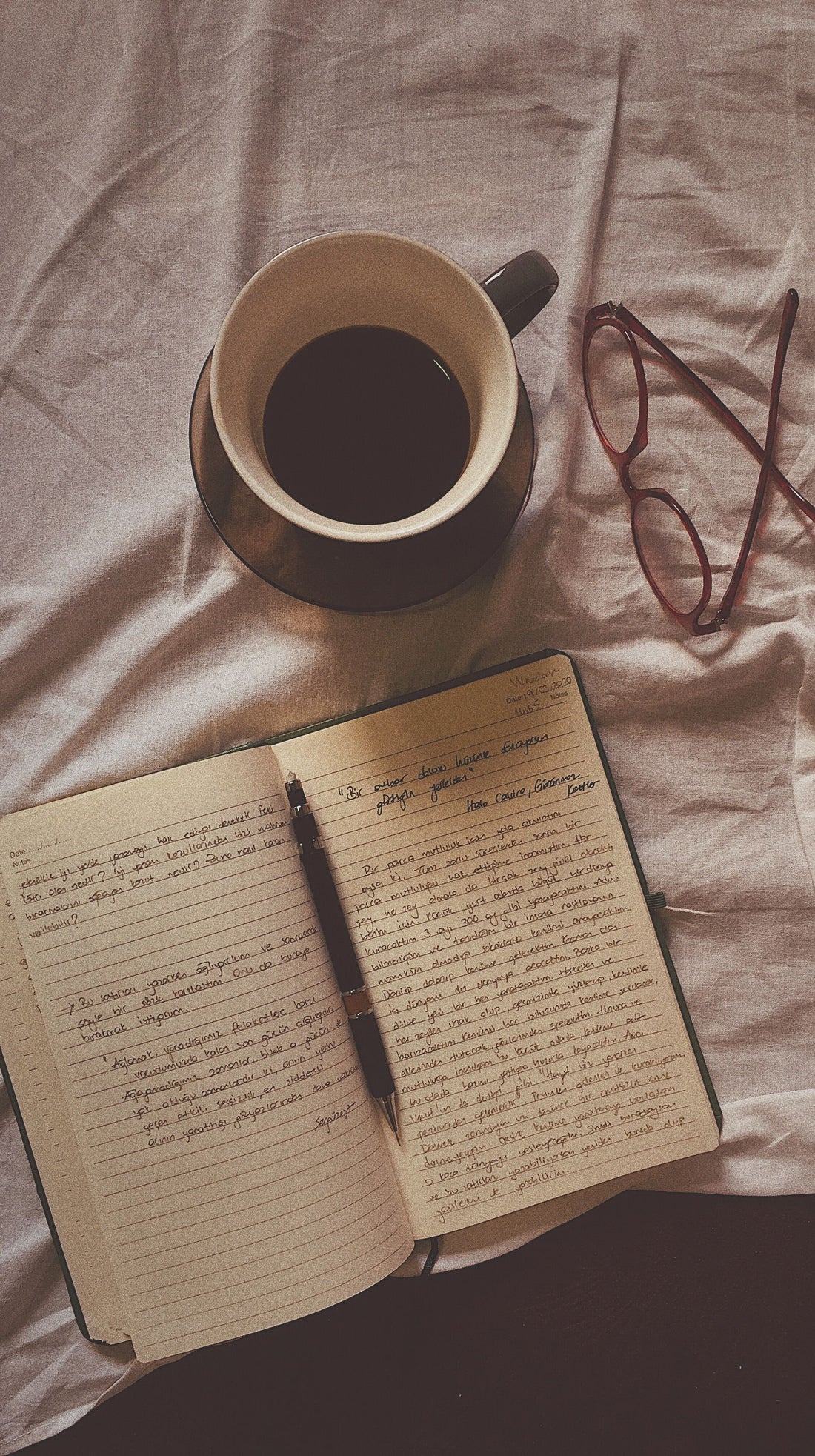 Coffee, open notebook, pen and glasses