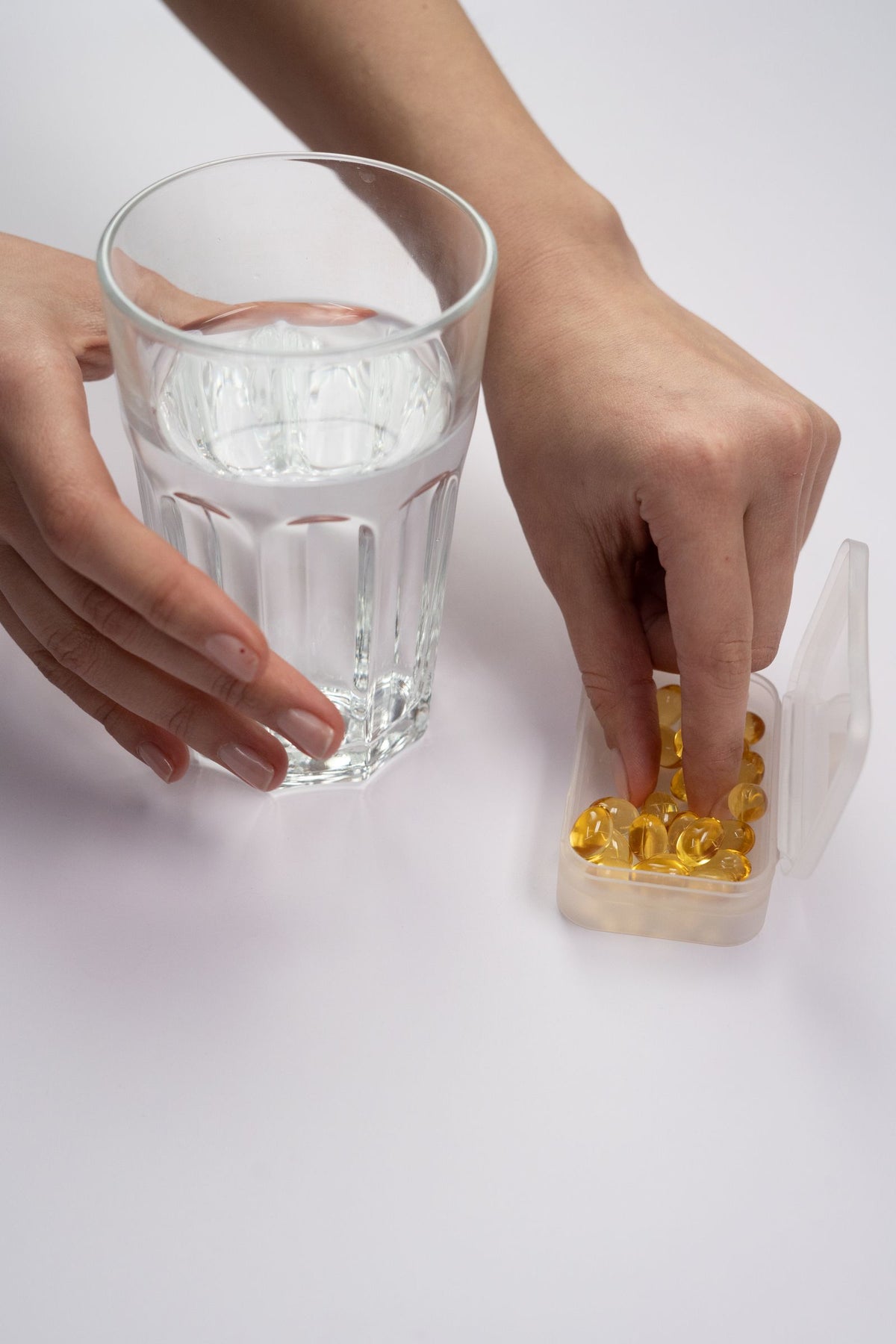 Supplements in a pill box beside a glass of water