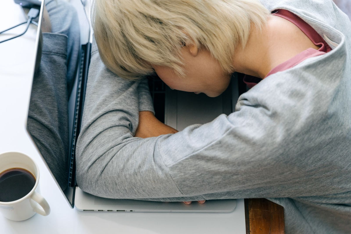 Woman resting her head on a laptop keyboard