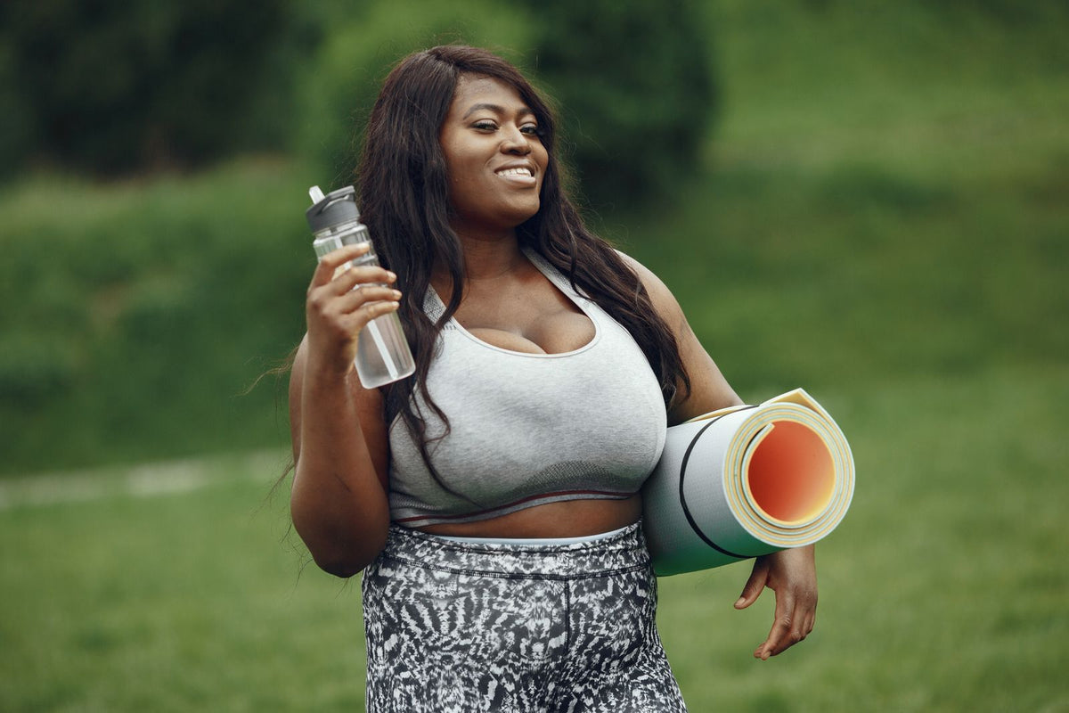 Woman with a yoga mat and water bottle outdoors