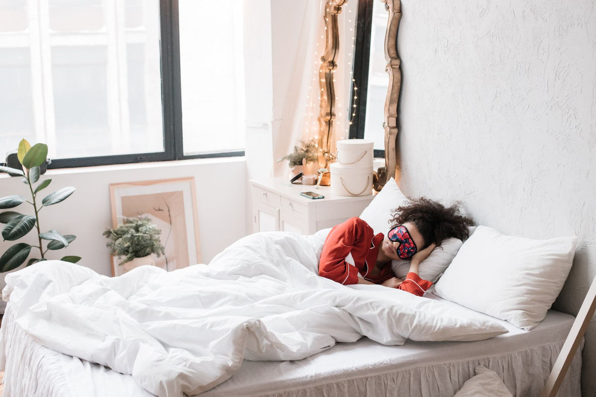 Woman resting in bed wearing a sleep mask