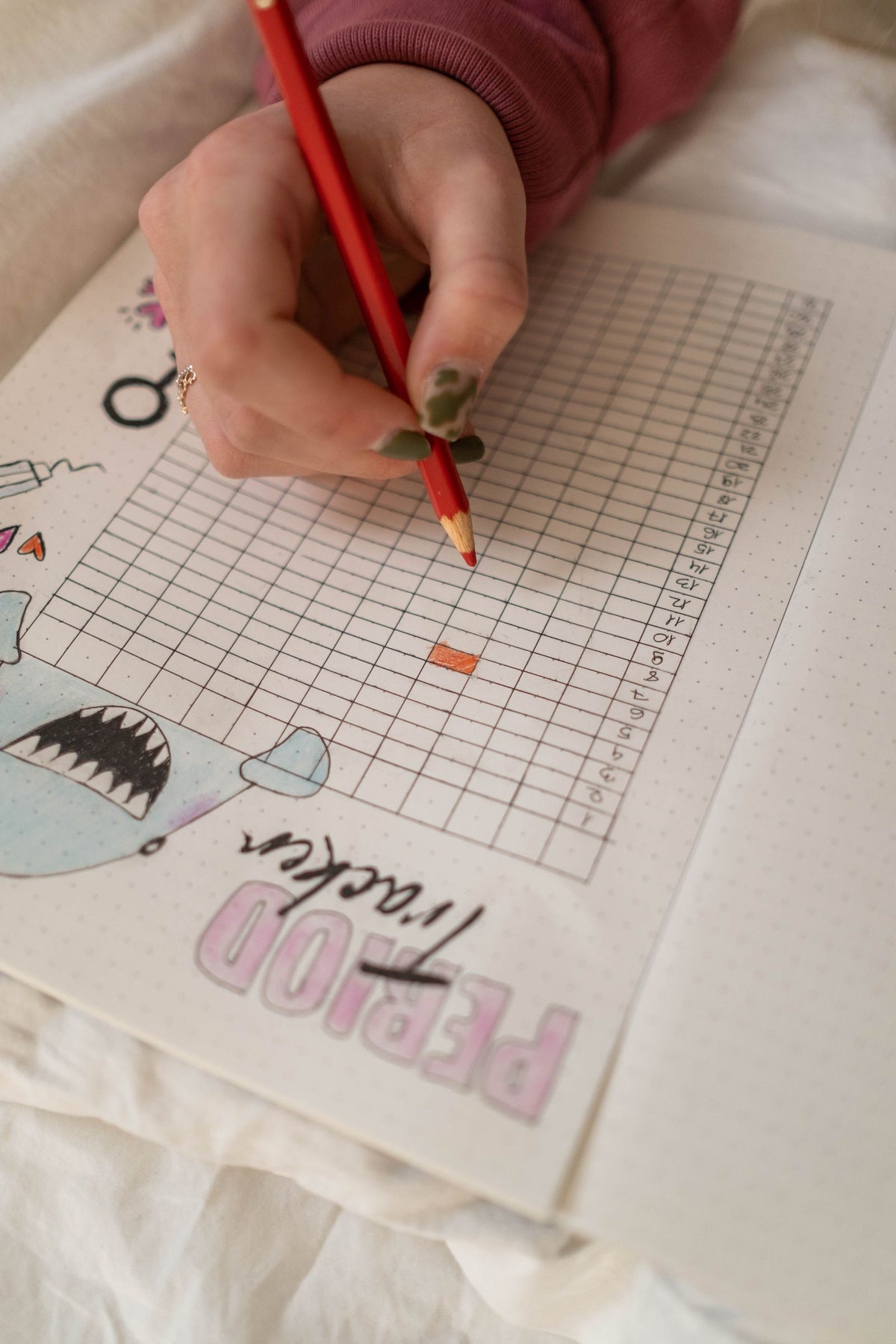 Hand drawing a period tracker in a notebook