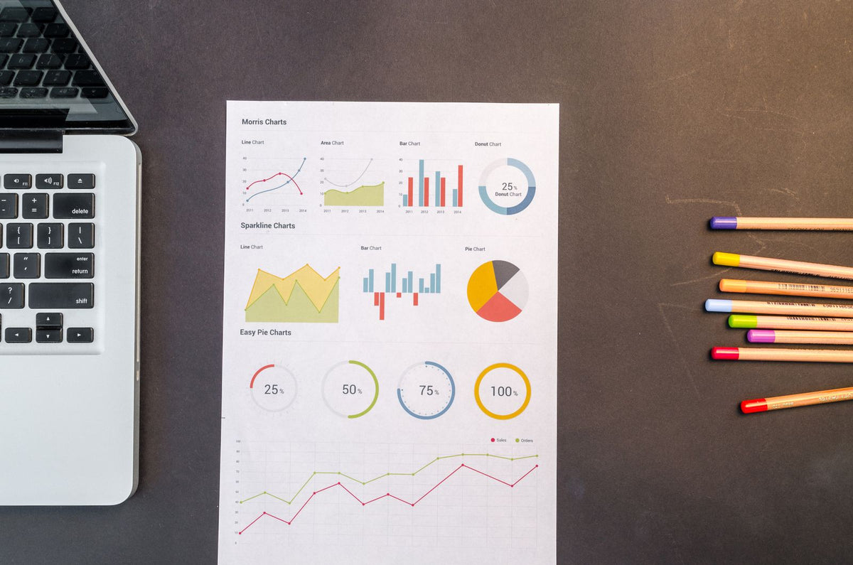 Charts and coloured pencils beside a laptop