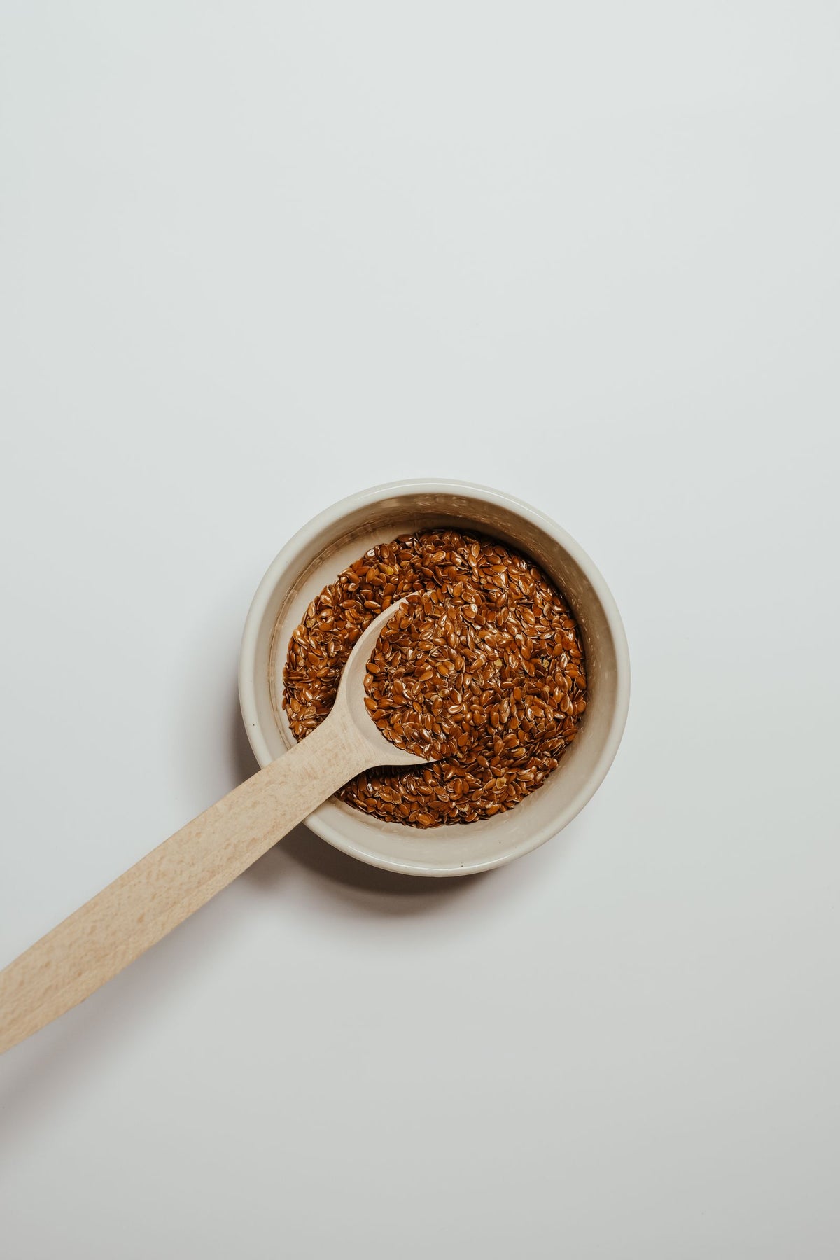 Flax seeds in a bowl with a wooden spoon