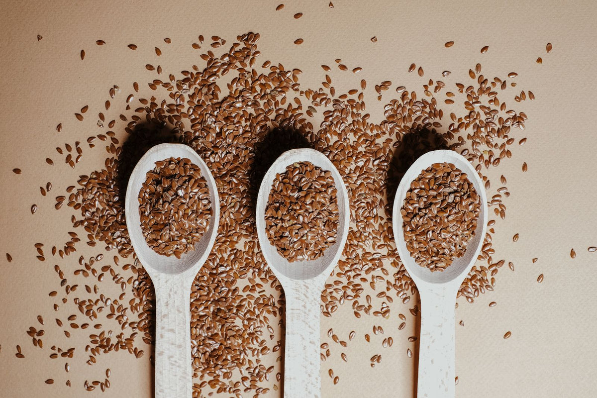 Three wooden spoons filled with flaxseeds