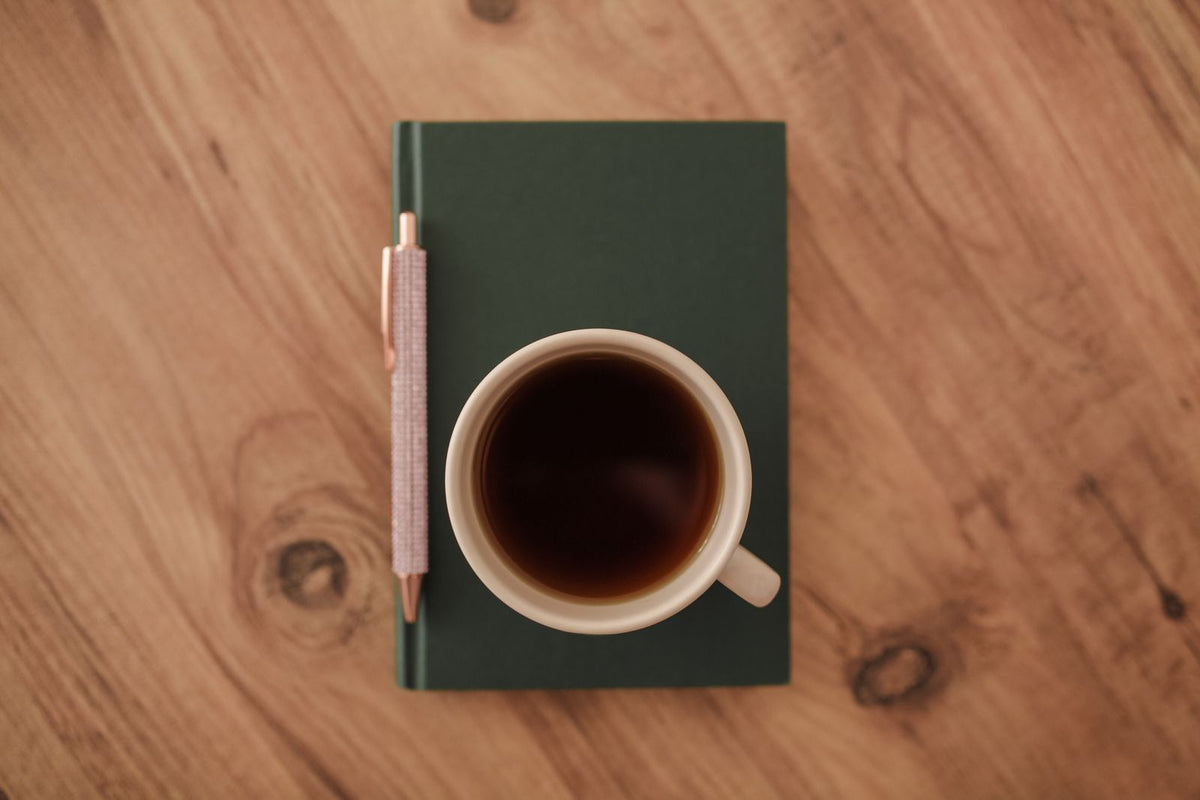 Coffee mug on a notebook with a pen