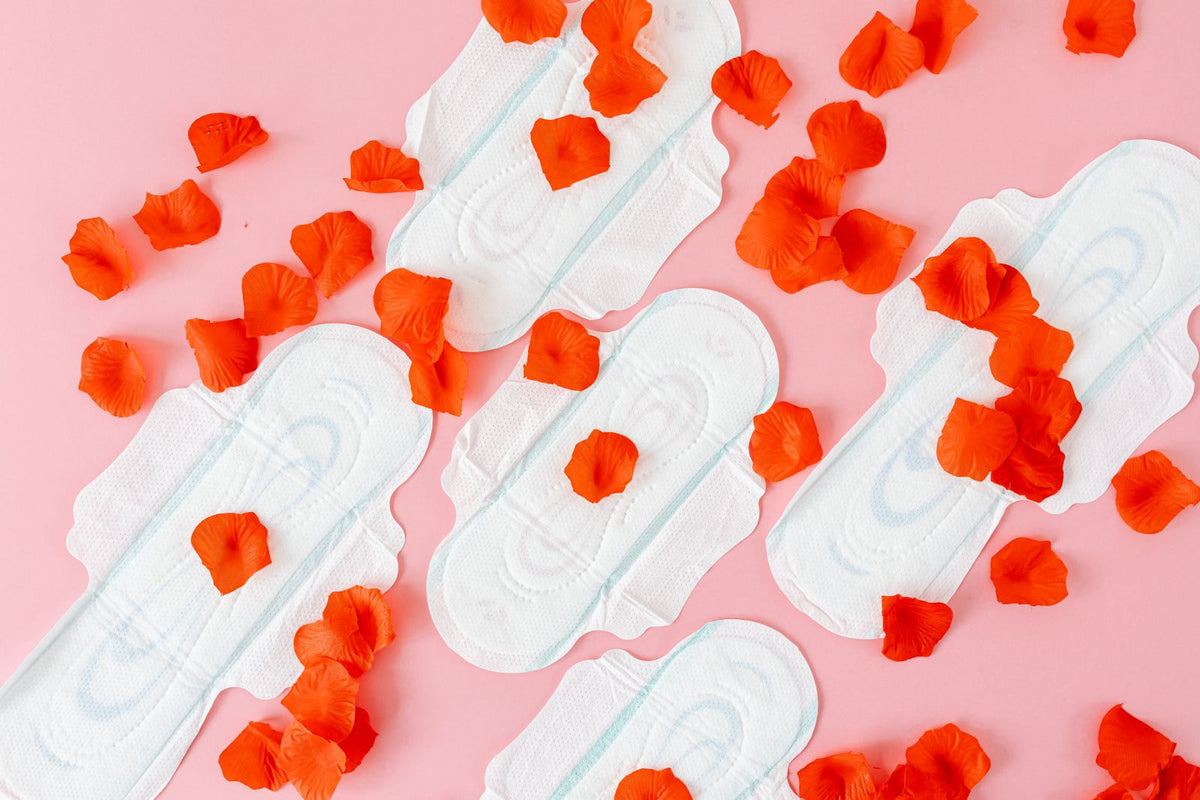 Sanitary pads with red petals on a pink background