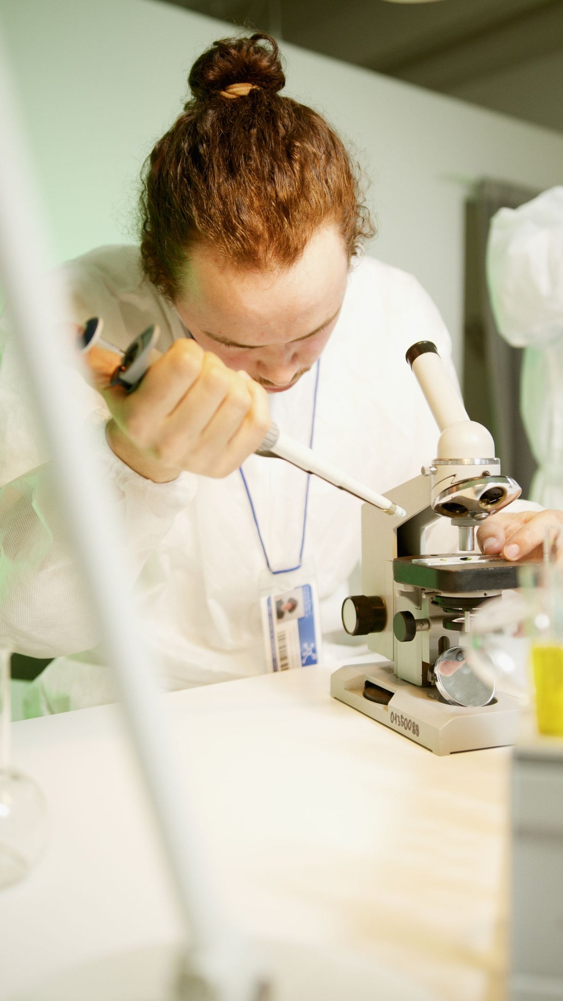 Scientist using a microscope and pipette