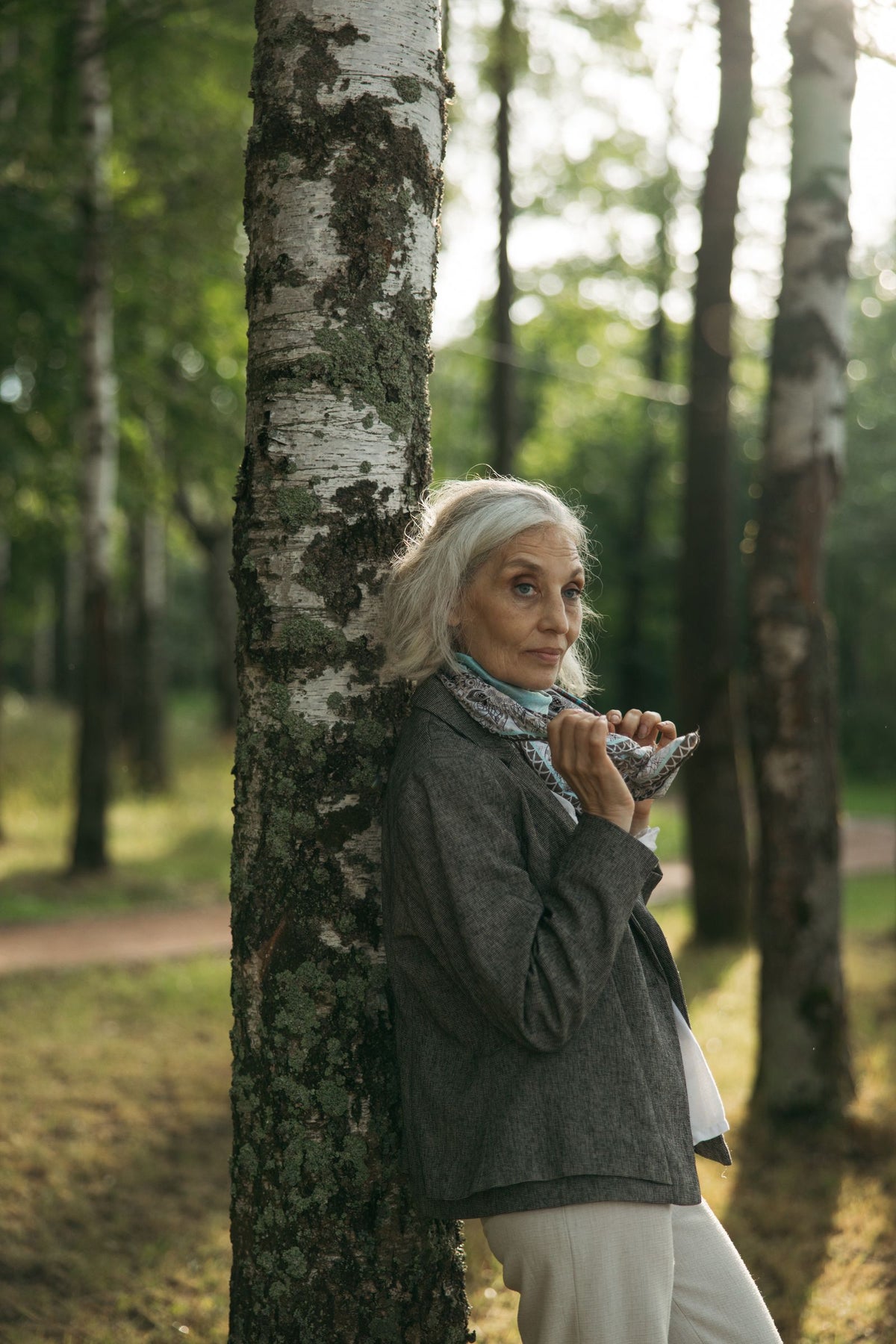 Woman leaning against a birch tree in a forest