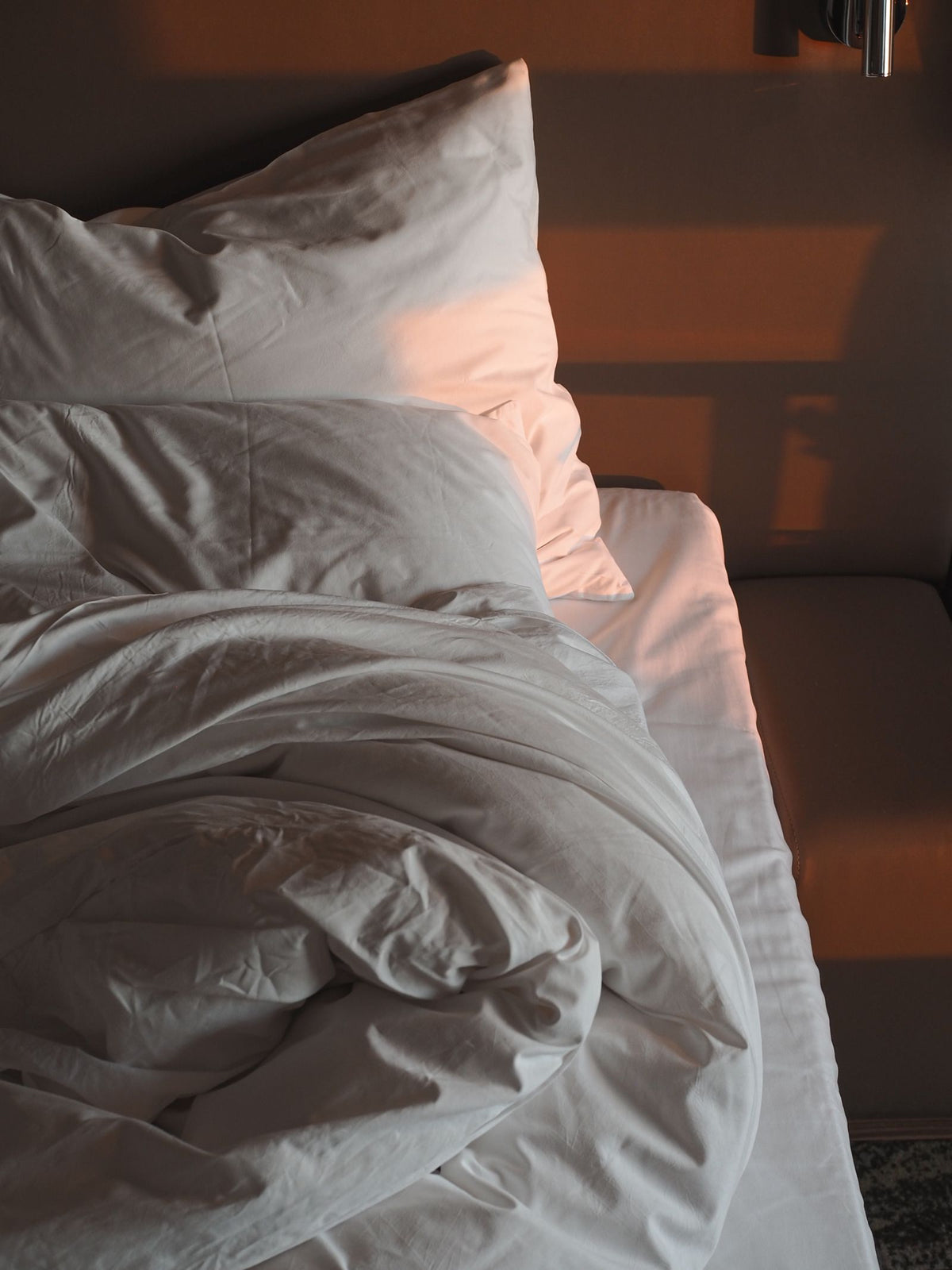 Bed with white linens in morning light