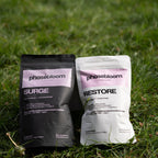 Two Phasebloom seed cycling kit product packages, 'Surge' and 'Restore', on grass.