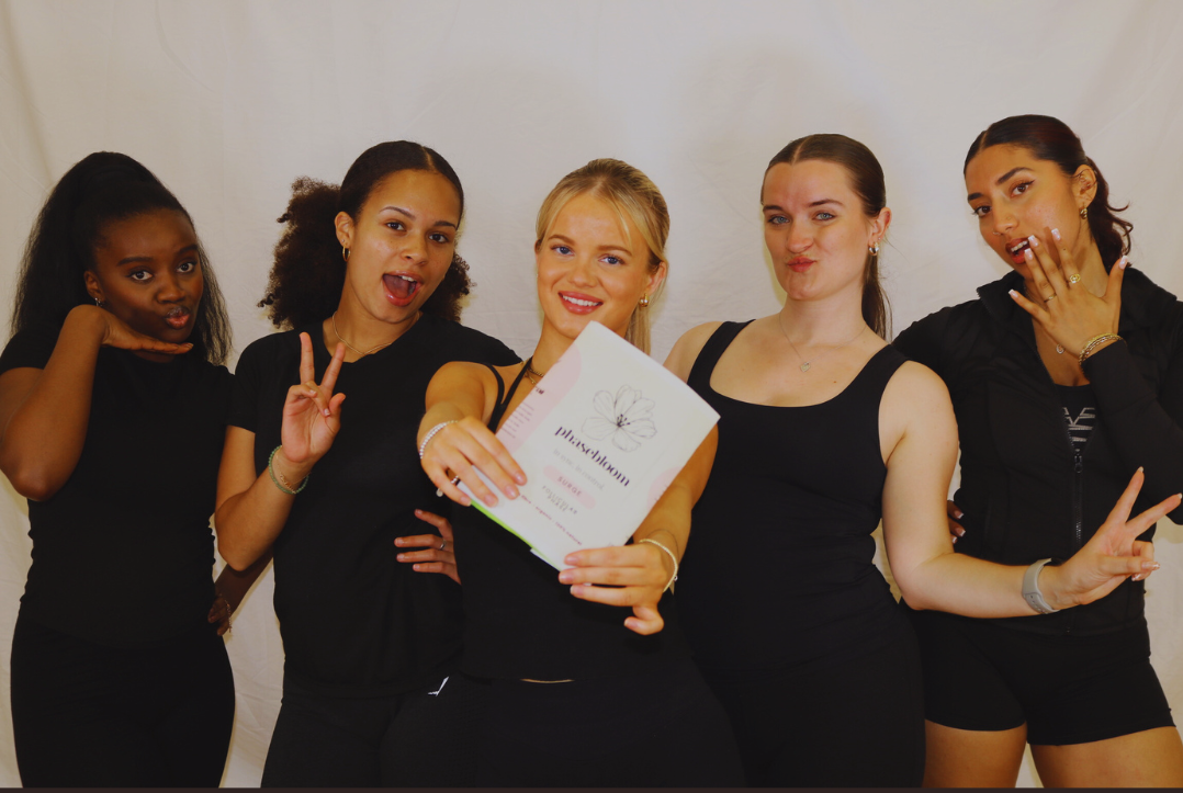 Five women in black outfits posing together, with one holding phasebloom seed cycling kit.